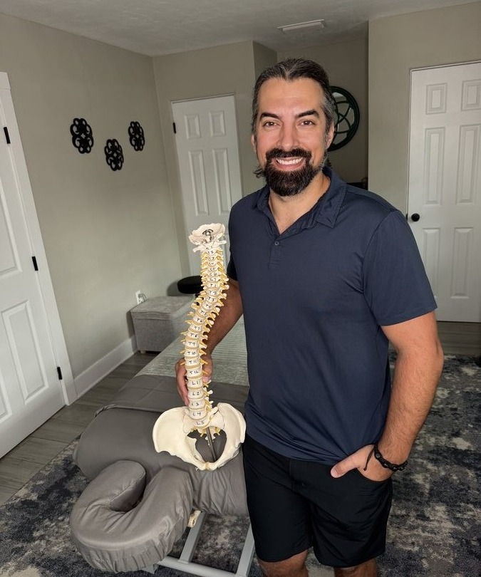 Alex holding a spinal anatomy model in the treatment room